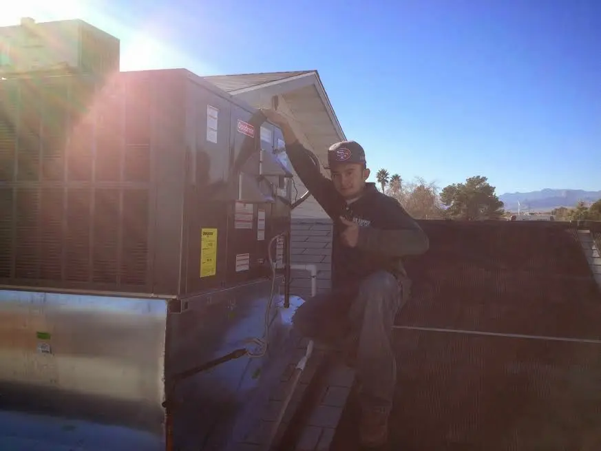 HVAC technician performing AC Tune-Up on a rooftop unit in Orchard Homes